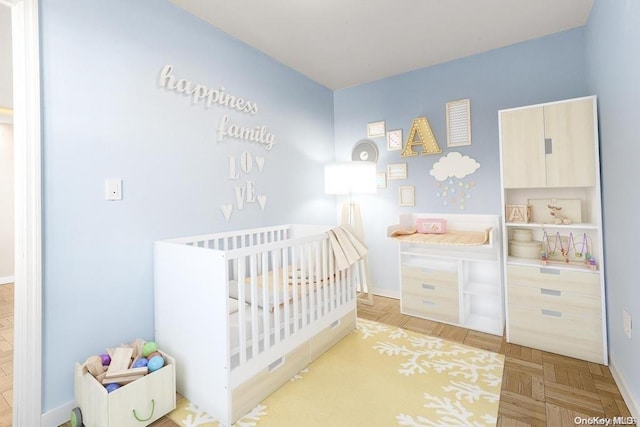 bedroom with light parquet flooring and a crib