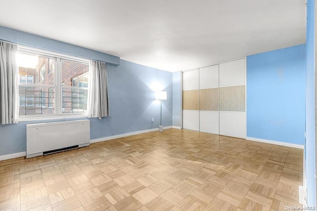 empty room with radiator heating unit and light parquet floors