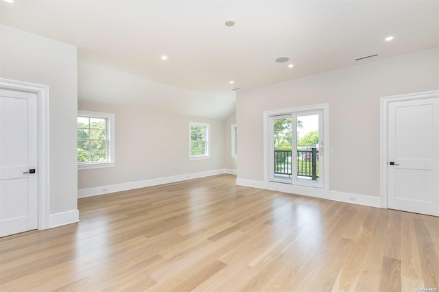 spare room with lofted ceiling, a wealth of natural light, and light hardwood / wood-style floors