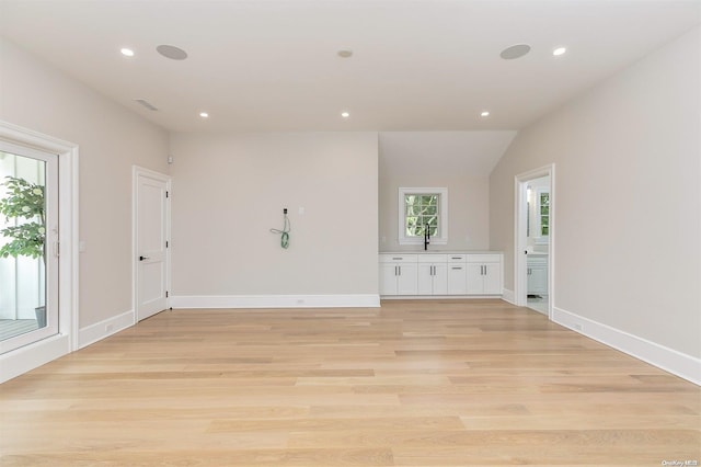 unfurnished room featuring lofted ceiling and light hardwood / wood-style floors