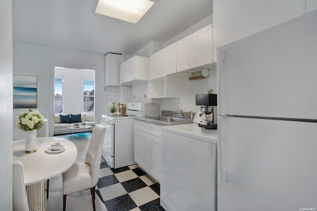 kitchen featuring decorative backsplash, white appliances, sink, washer / dryer, and white cabinetry