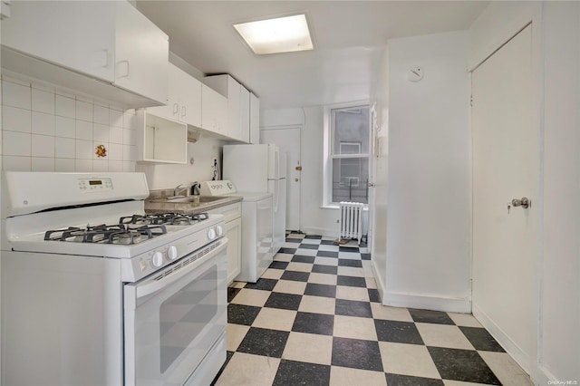 kitchen with radiator, white cabinetry, gas range gas stove, backsplash, and washer / dryer