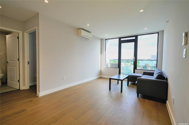 living area featuring hardwood / wood-style floors, french doors, and a wall mounted AC