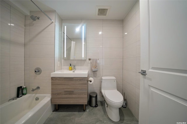 full bathroom featuring washtub / shower combination, vanity, toilet, and tile walls