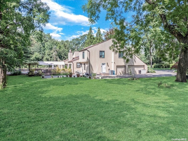 rear view of property with central air condition unit, a yard, and a garage