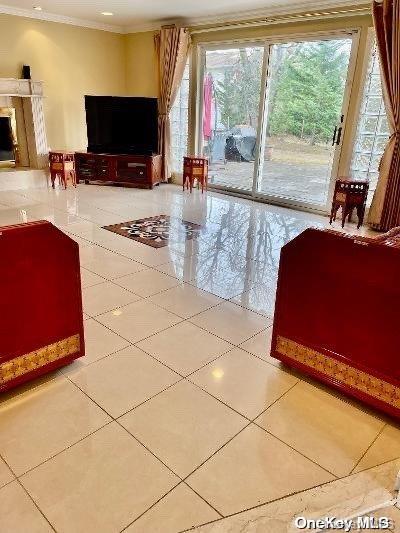 unfurnished living room with light tile patterned floors and crown molding