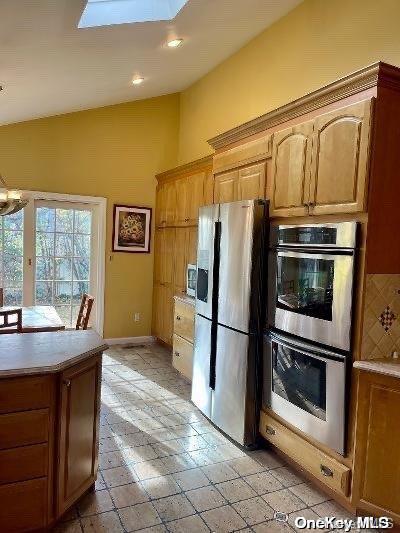 kitchen with a skylight, decorative backsplash, and stainless steel appliances