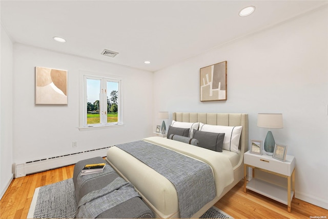 bedroom with hardwood / wood-style flooring and baseboard heating