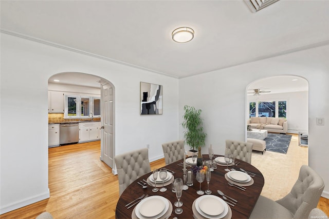 dining room featuring ceiling fan, light hardwood / wood-style flooring, ornamental molding, and sink