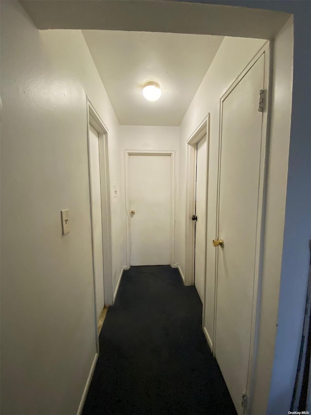 corridor featuring dark colored carpet