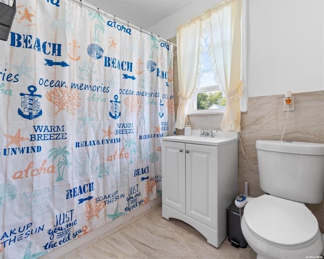 bathroom with a shower with shower curtain, vanity, toilet, and tile walls