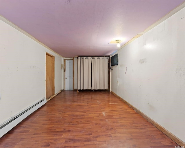 empty room with hardwood / wood-style flooring and a baseboard heating unit