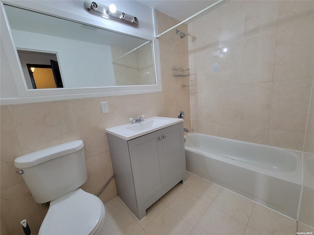 full bathroom with vanity, toilet, tiled shower / bath, and tile walls