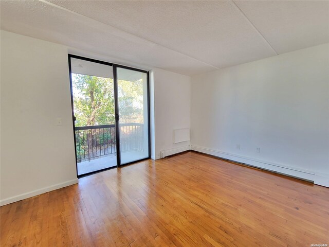 empty room featuring light hardwood / wood-style floors, a textured ceiling, and a wall of windows