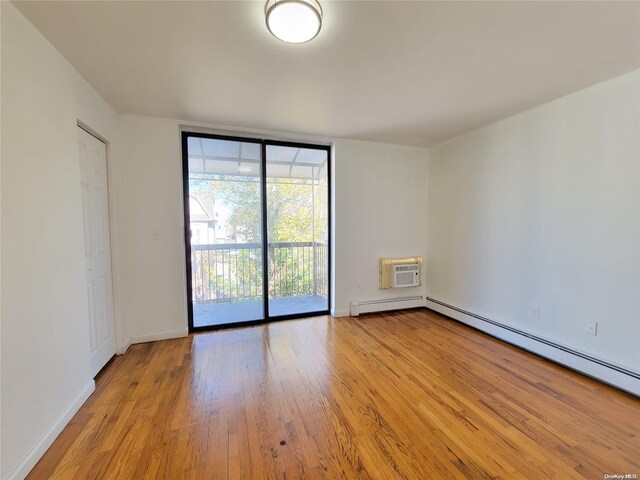 spare room featuring an AC wall unit, a baseboard heating unit, and light wood-type flooring