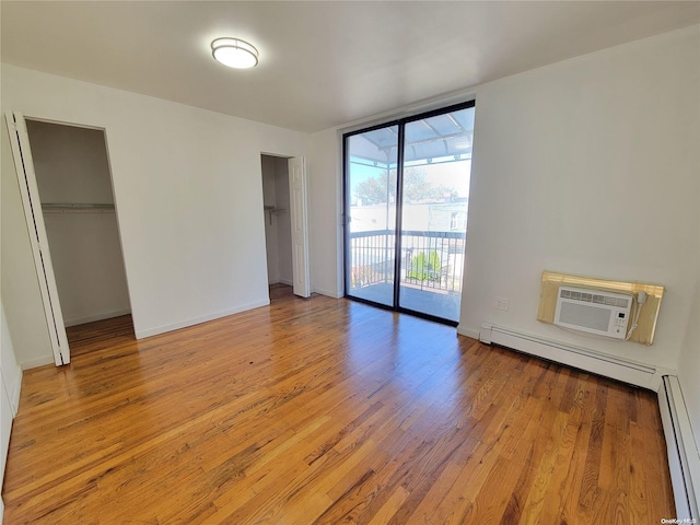 unfurnished bedroom with baseboard heating, a closet, access to outside, and light hardwood / wood-style flooring