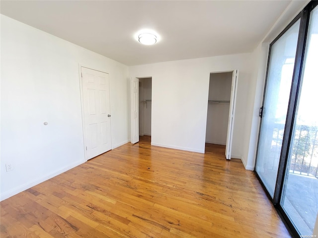 unfurnished bedroom featuring multiple closets and light hardwood / wood-style floors