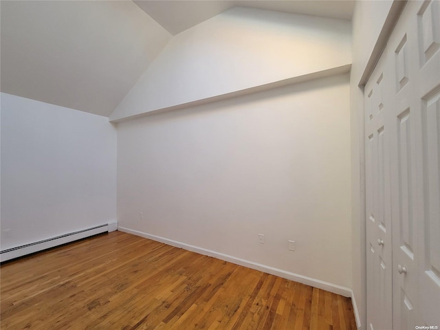 additional living space featuring hardwood / wood-style floors, baseboard heating, and lofted ceiling