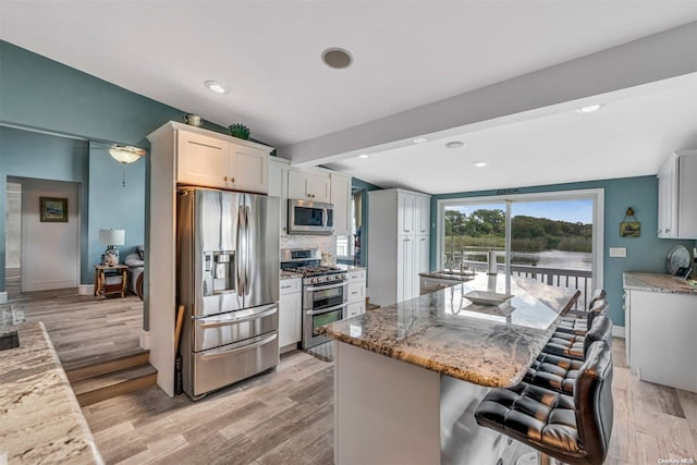 kitchen with white cabinets, light wood-type flooring, light stone countertops, and stainless steel appliances