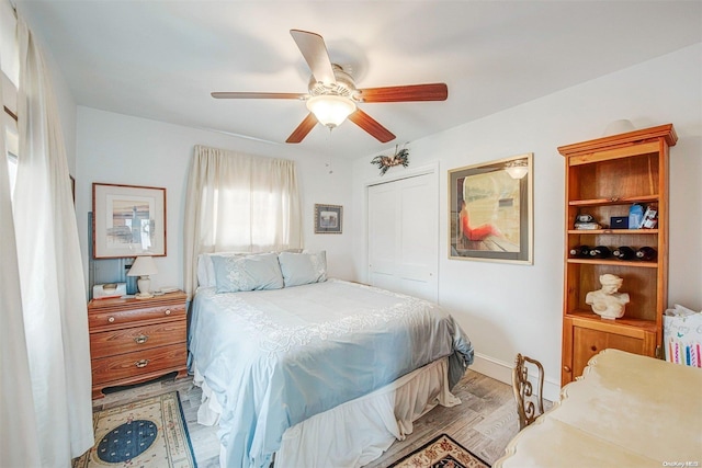 bedroom with a closet, light hardwood / wood-style flooring, and ceiling fan