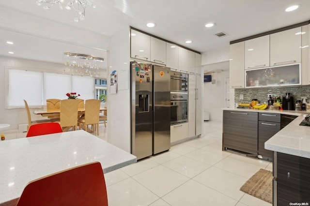 kitchen featuring white cabinetry, light stone countertops, tasteful backsplash, stainless steel fridge, and light tile patterned floors