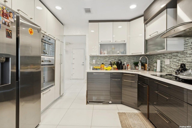 kitchen featuring stainless steel fridge, tasteful backsplash, wall chimney exhaust hood, sink, and white cabinets