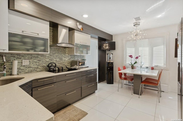 kitchen featuring black electric stovetop, backsplash, wall chimney exhaust hood, pendant lighting, and white cabinets