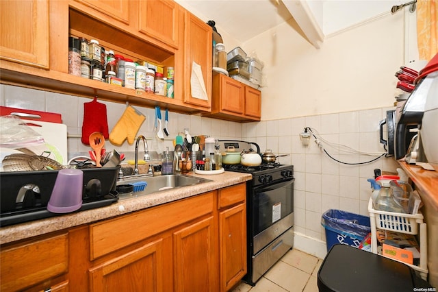 kitchen featuring sink, light tile patterned floors, black gas range oven, and tile walls