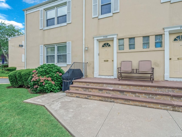 property entrance with stucco siding and a lawn