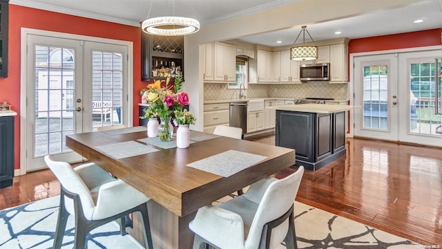 dining space with crown molding, light hardwood / wood-style flooring, and french doors