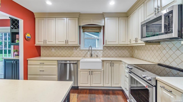 kitchen with dark hardwood / wood-style flooring, appliances with stainless steel finishes, sink, and cream cabinets