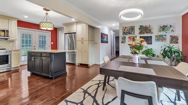 kitchen featuring appliances with stainless steel finishes, tasteful backsplash, cream cabinetry, decorative light fixtures, and french doors