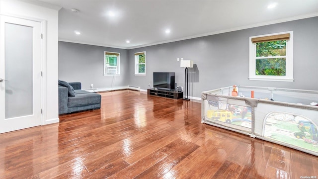 living room with cooling unit, hardwood / wood-style floors, ornamental molding, and baseboard heating