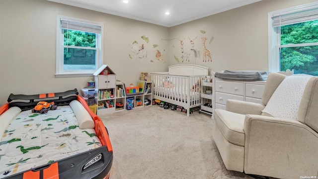 bedroom with crown molding, a nursery area, and carpet flooring