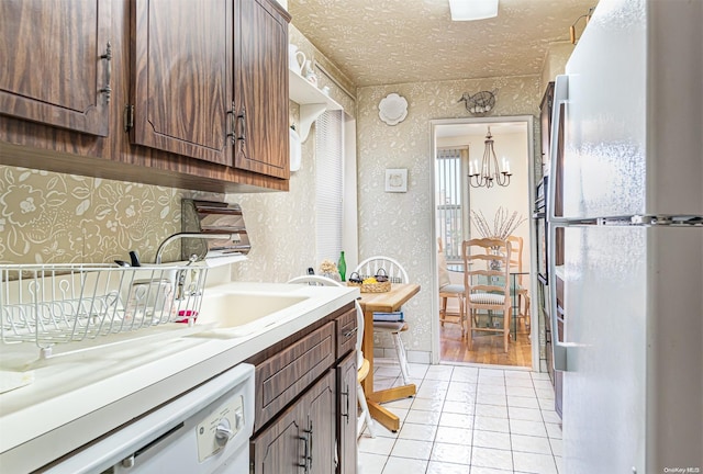 kitchen featuring dark brown cabinets, white appliances, light tile patterned floors, an inviting chandelier, and hanging light fixtures