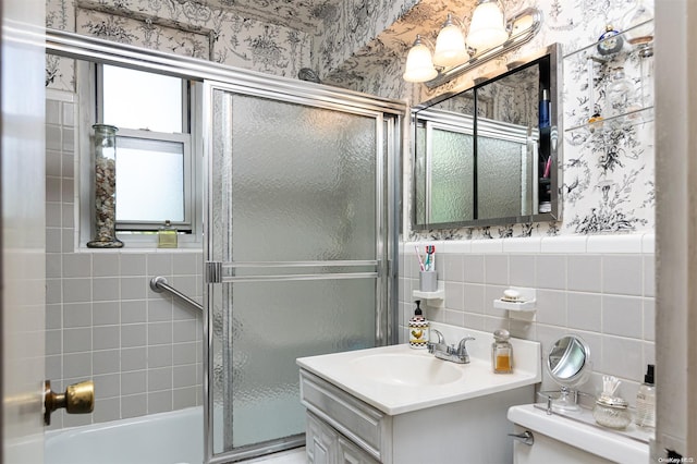 full bathroom featuring vanity, toilet, tile walls, and bath / shower combo with glass door