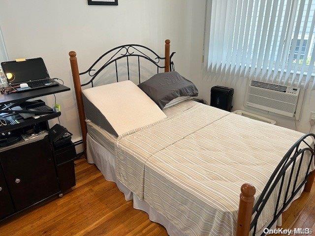 bedroom featuring baseboard heating and dark hardwood / wood-style floors