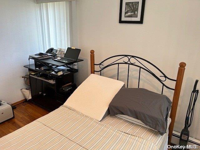 bedroom with wood-type flooring and a baseboard radiator