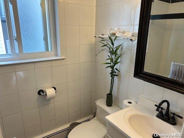 bathroom with decorative backsplash, tile walls, and toilet