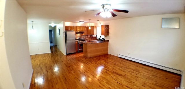 kitchen with kitchen peninsula, appliances with stainless steel finishes, tasteful backsplash, dark wood-type flooring, and pendant lighting