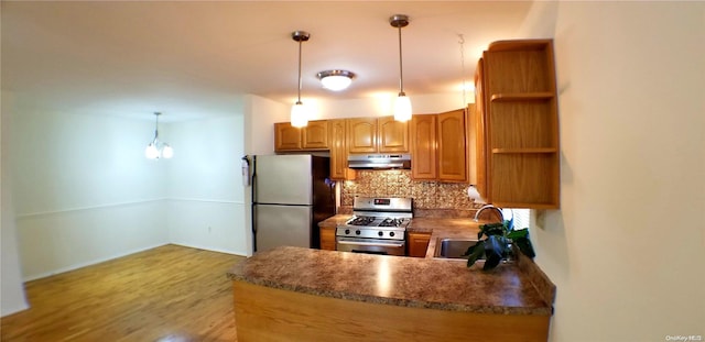 kitchen with kitchen peninsula, sink, stainless steel appliances, and decorative light fixtures