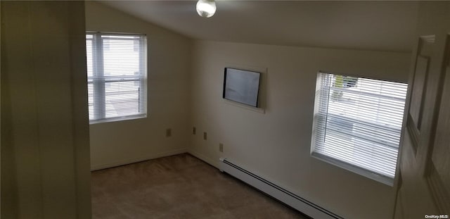 carpeted empty room with a baseboard radiator, vaulted ceiling, and a wealth of natural light