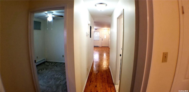 hallway featuring baseboard heating and dark hardwood / wood-style flooring