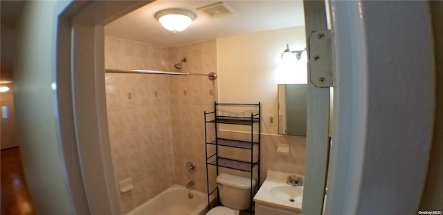 full bathroom with vanity, tiled shower / bath combo, toilet, and backsplash