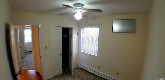 unfurnished bedroom with ceiling fan, baseboard heating, and multiple windows