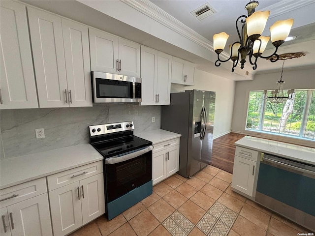 kitchen featuring appliances with stainless steel finishes, backsplash, crown molding, a chandelier, and white cabinetry