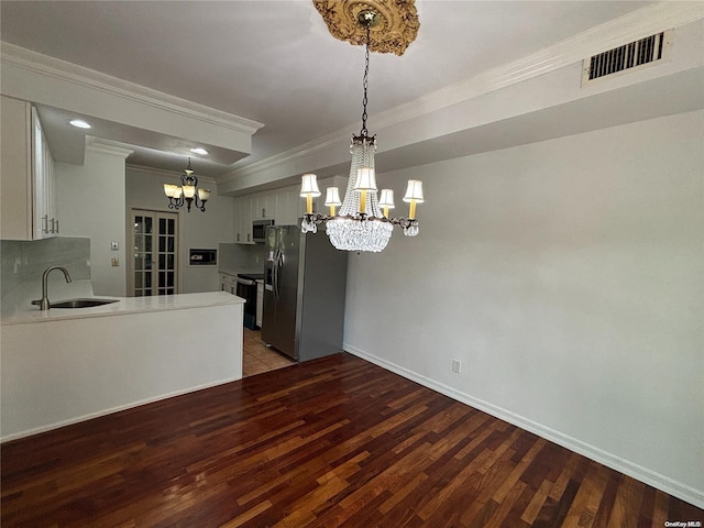 kitchen featuring ornamental molding, appliances with stainless steel finishes, a chandelier, white cabinets, and hardwood / wood-style flooring