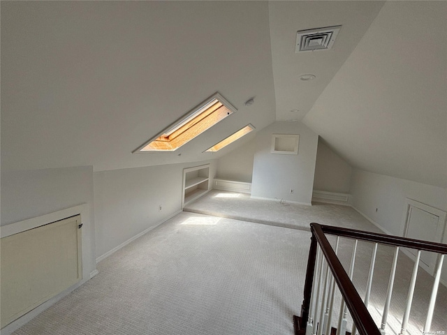 additional living space with vaulted ceiling with skylight and light colored carpet