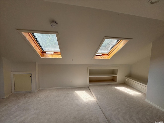 bonus room featuring vaulted ceiling with skylight, built in features, and light carpet