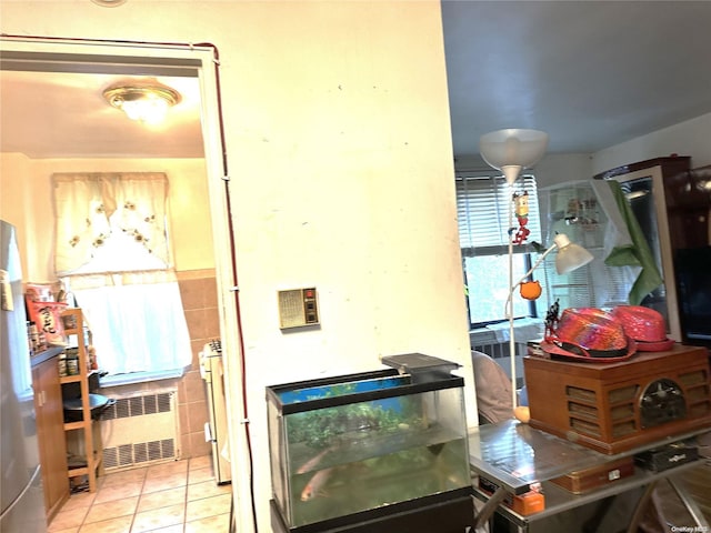 kitchen with radiator heating unit, light tile patterned floors, and tile walls